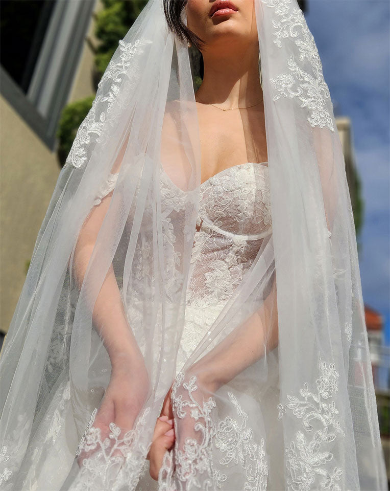 dramatic full italian tulle veil with heavy lace borders wrapped around bride wearing corset style off shoulder wedding gown - chiara bridal veil at Kezani