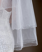 wedding and bridal veils - elegant elbow length veil with extra sparkle crystal edge - two tier - on model with dark hair - close up - Demi at Kezani