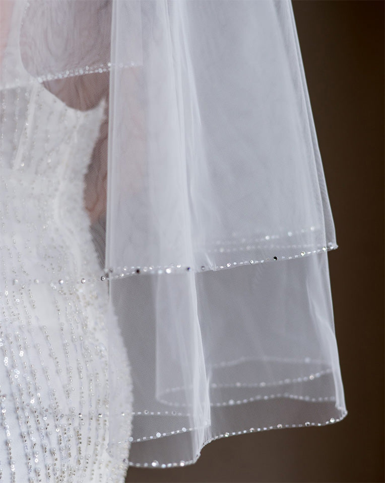 wedding and bridal veils - elegant elbow length veil with extra sparkle crystal edge - two tier - on model with dark hair - close up - Demi at Kezani