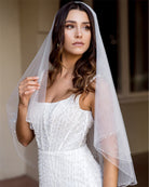 wedding and bridal veils - elegant elbow length veil with extra sparkle crystal edge - two tier - on model with dark hair - side view - Demi at Kezani
