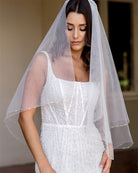 wedding and bridal veils - elegant elbow length veil with extra sparkle crystal edge - two tier - on model with dark hair - front view - Demi at Kezani