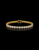 Gold 4mm tennis bracelet with crystals on a black background