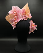 A decorative floral orchid fascinator with ecru fan-like leaves with orchid side comb, displayed on a black mannequin head against a dark studio background.