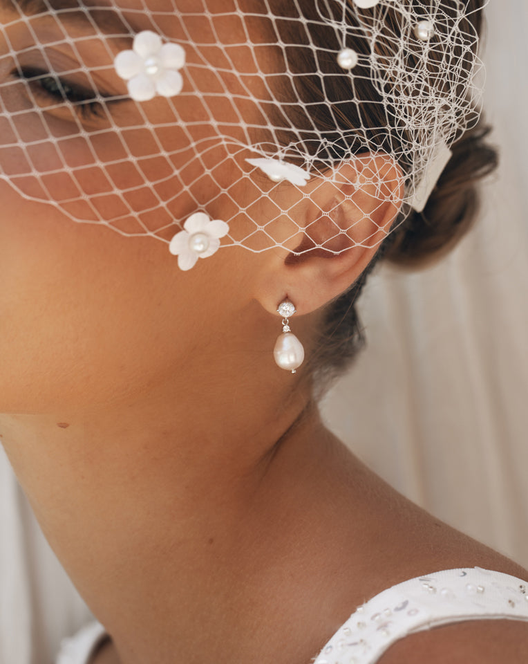 close up of bride wearing birdcage veil with pearl and crystal earrings