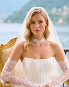 Beautiful bride in corset bodice with lace sleeves wearing a delicate lace choker by Kezani jewellery sitting in chair at lake como