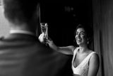 Black and white image of bride and groom toasting champaign bridal earings white opal boho earing called pipa by kezani jewellery